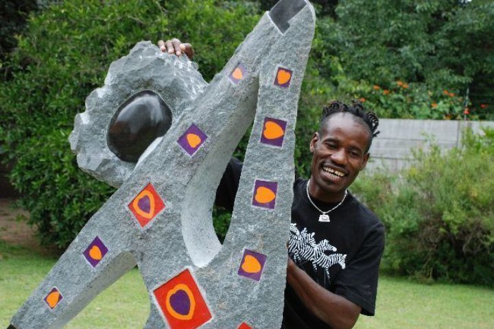 Zimbabwean stone sculptor Dominic Benhura posing with one of his artworks