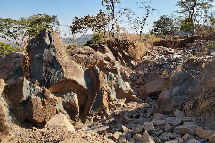 Zimbabwean springstone quarry with loose rocks on the ground and trees in the background