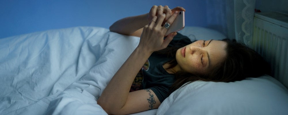femme regarde smartphone dans le lit