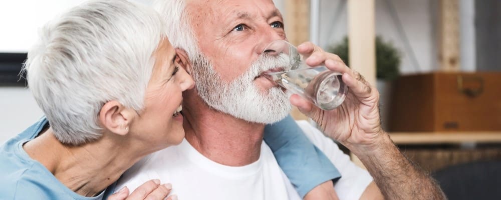 homme age qui boit un verre d'eau