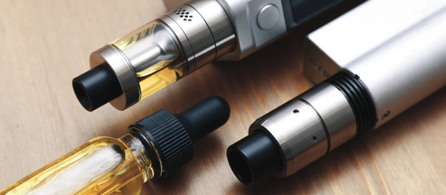 three open system vapes on light wood surface