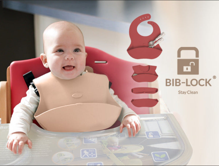 A happy baby wearing a tan Ruby Wrapp Silicone Bib from Abiie