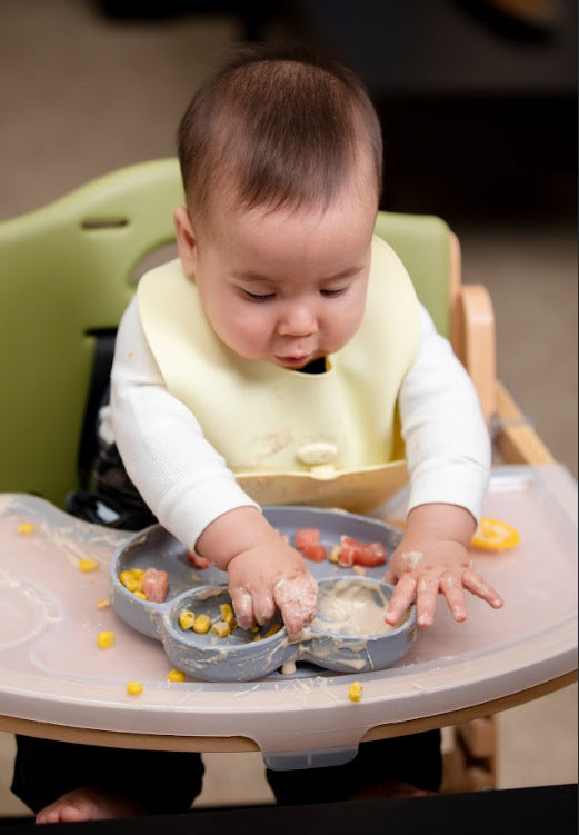 Baby eating holiday baby food while wearing Ruby Wrapp bib