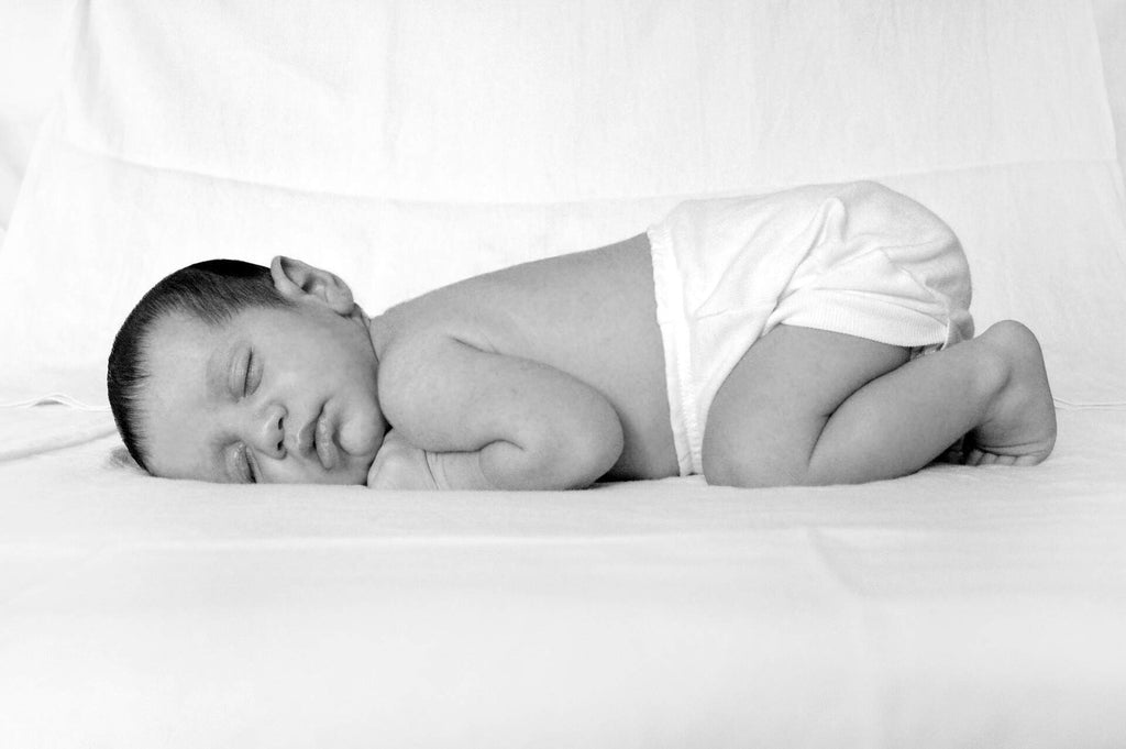 baby sleeping in diaper in black and white