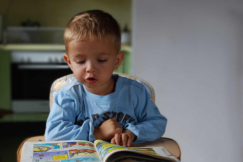  boy reading a book in a high chair