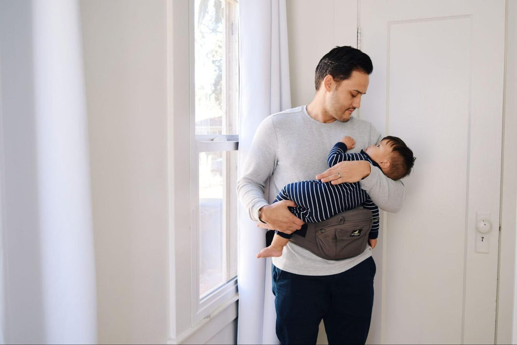 Dad holds son with the help of the hip carry mode