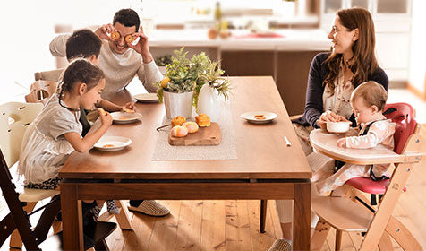 family laughing around table while eating fruit