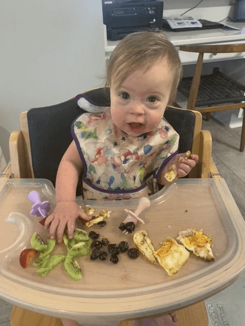girl with down syndrome eating in high chair