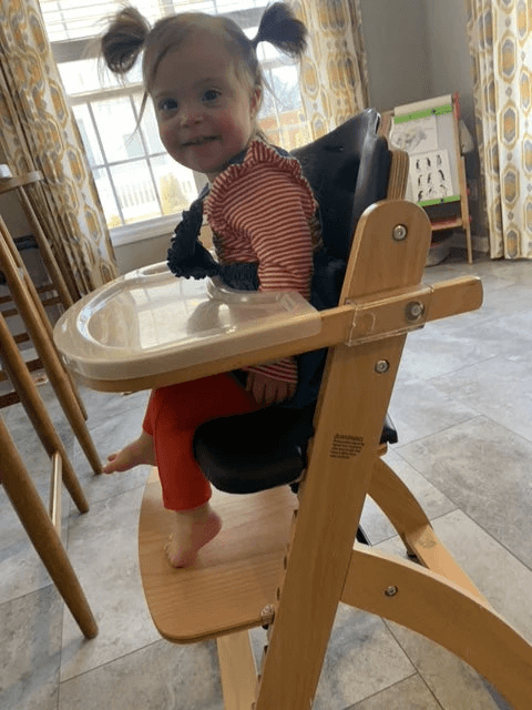 girl sitting in high chair without food