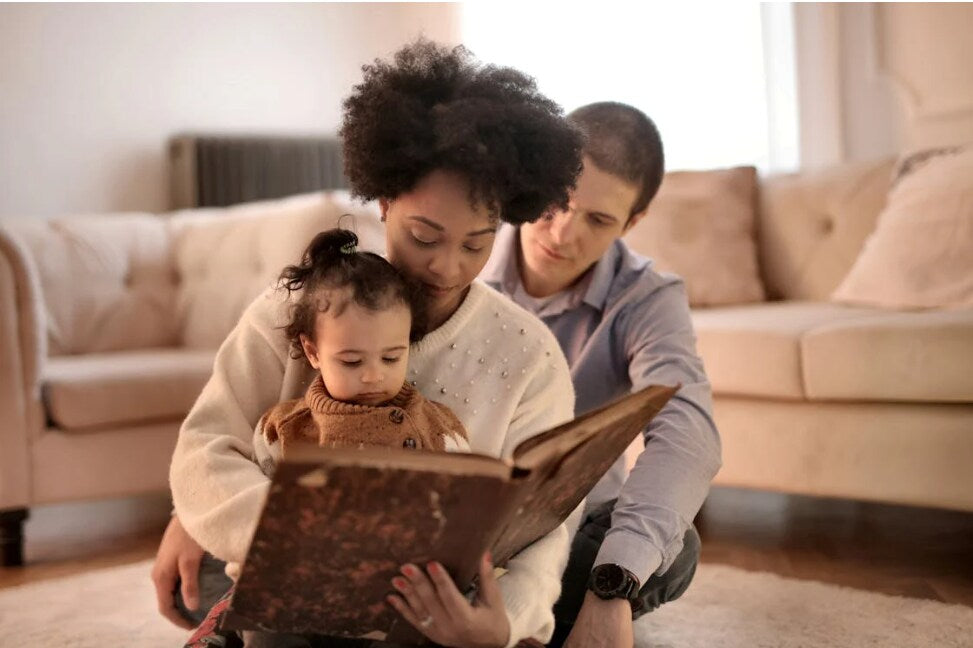 parents reading a book to baby