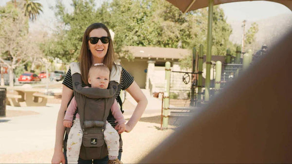 woman in shades carrying baby in front