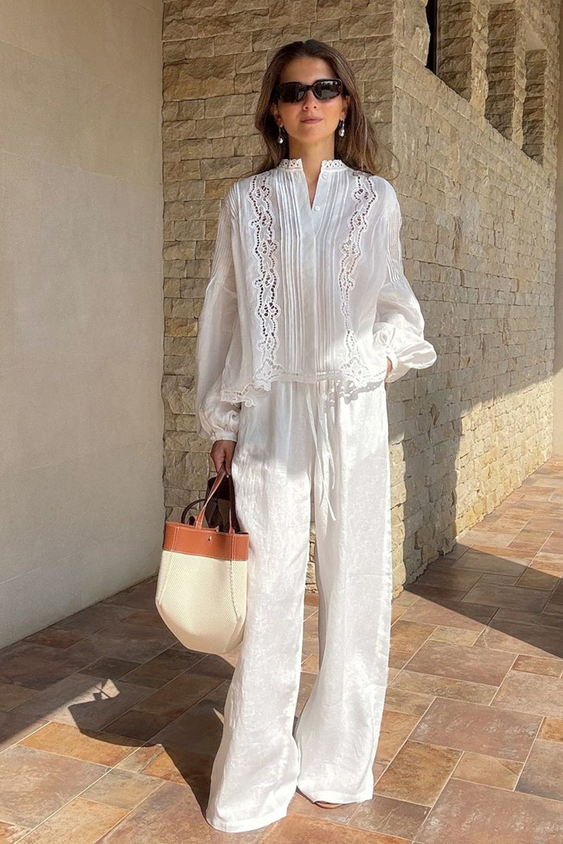 Model styled in pleated hollow embroidered blouse and linen trousers, embracing French summer chic with breathable fabric and relaxed tailoring