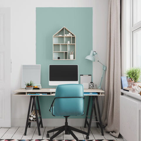 Wooden study desk with blue chair and blue colour block on the wall. 