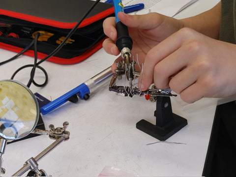 Hands holding a soldering iron and assembling Jitterbug kit