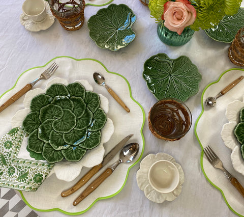 table setting of green plate over scalloped cotton fabric placemat