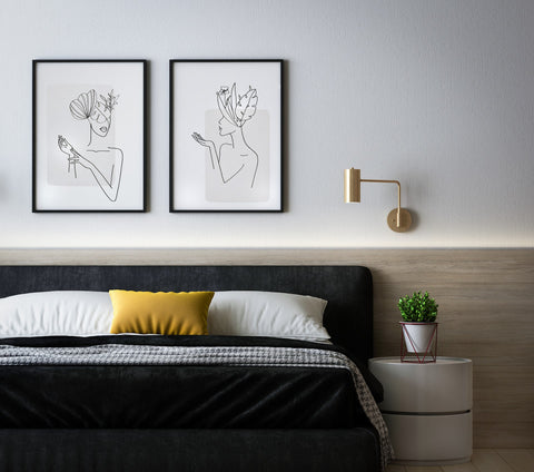 Black bed with line art of two wall art of women hanging on top