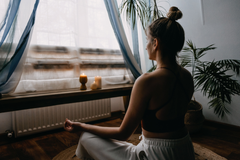 Femme yogi assise en lotus devant grande fenetre pour une séance de méditation- my shop yoga