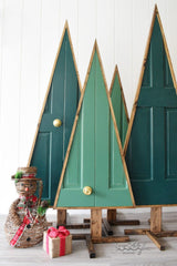 Four Christmas trees made out of doors. They are painted green. 