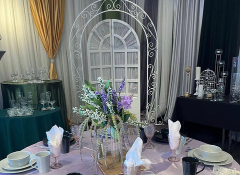 A beautiful table set up in the Party Stuff showroom. There is a lilac-coloured table cloth with turquoise dishes, and a flower centrepiece. 