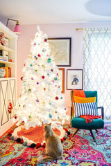A colourful room with a white Christmas tree. The tree has vibrant ornaments. 