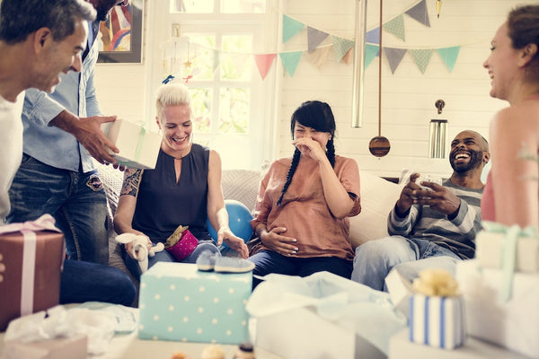 Female couple smiling while opening gifts at a baby shower