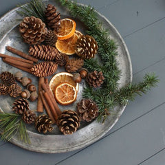 Woodland Christmas Table Setting Ideas: a tin tray with pine cones, twigs, pine, dried orange slices, and cinnamon sticks. 