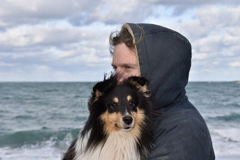 chien avec son maitre dans les bras au bord de la mer