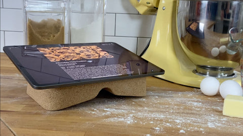 Cork Booklift by Revision holding an iPad with cookie recipe on messy wooden counter top in front of yellow mixer..