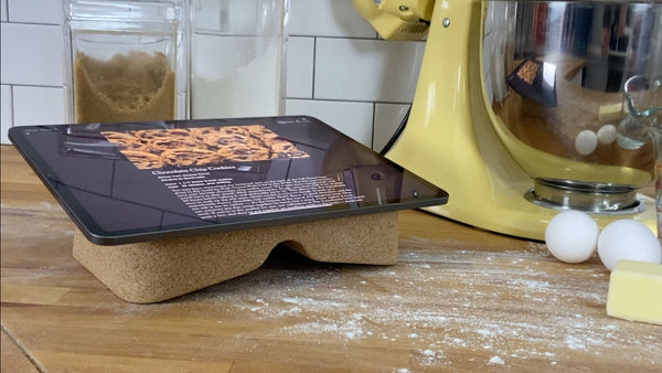 Revision Cork Booklift holds Apple iPad displaying New York Times cooking recipe on messy kitchen counter top with yellow Kitchenaide mixer in the backround. 