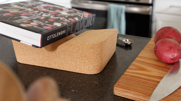 Cork Booklift by Revision holding a cookbook next to a cutting board with knife and potatos.