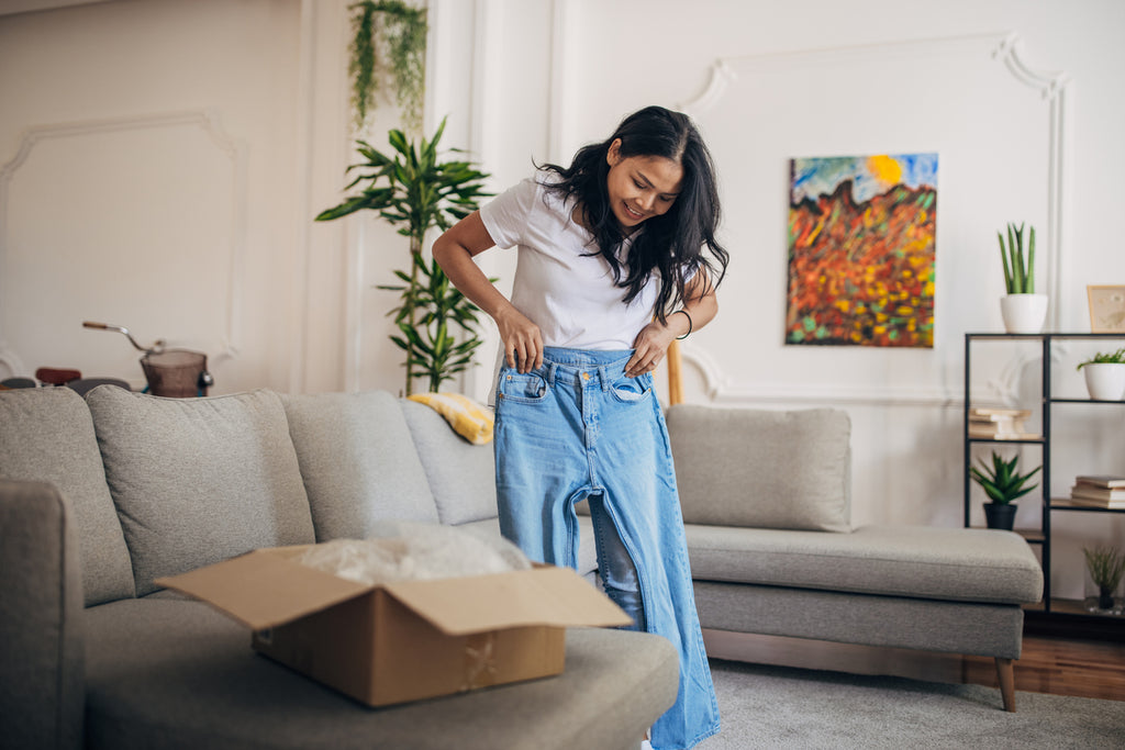 Young Asian women trying on a pair of jeans she bought online