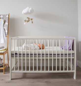 A white crib with a baby in it