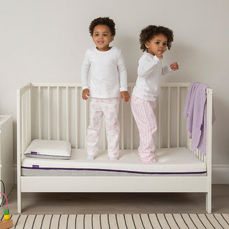 two toddlers standing on top of a cot