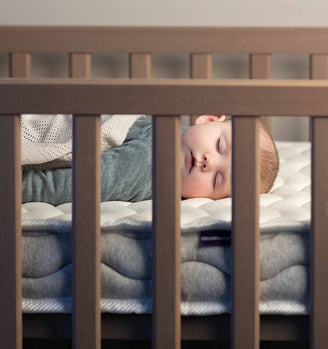 Close up of baby sleeping in a cot laying on their back
