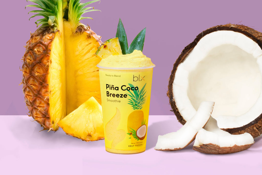 Pina Cocoa Breeze smoothie standing next to natural ingredients like coconut and pineapple