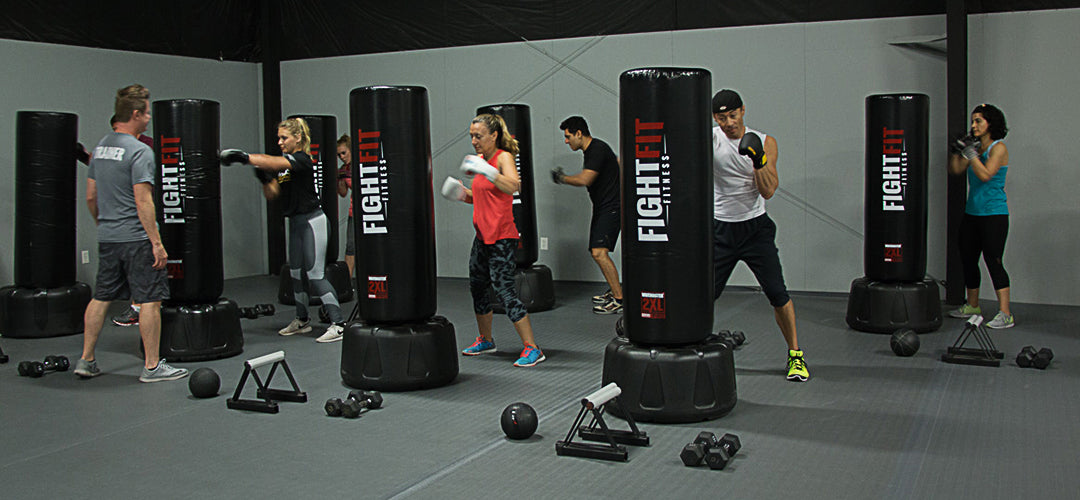People punching custom freestanding bags with the FightFit logo