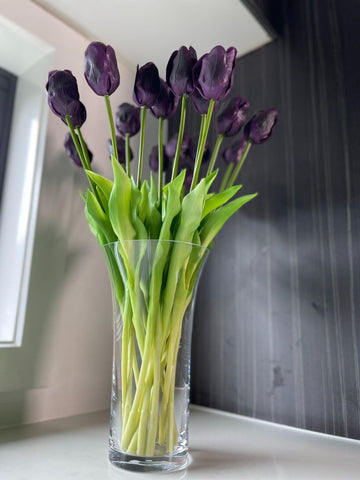 Artificial floral stems in vase placed on benchtop near window