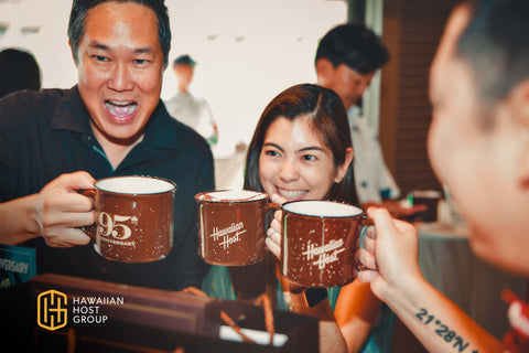 Guests of the event enjoying hot coco bar with branded 95th Anniversary campfire mugs.