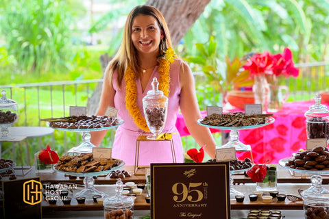 Theresa Tuxhorn standing behind chocolate bar activation station at Hawaiian Host's 95th Anniversary Event.