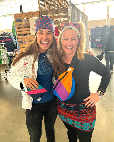 Two women smiling with bright colored upcycled bags