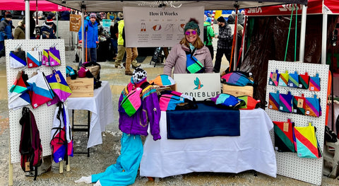 Woman smiling selling colorful bags made from upcycled clothing