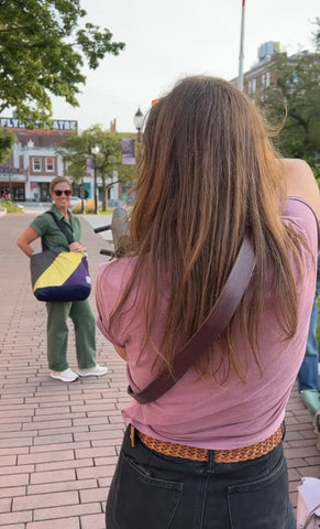 Photographer photographing women wearing bright colored sling bag in a city