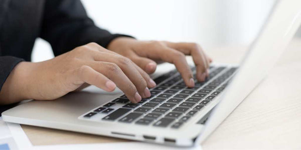 Hands typing on a laptop