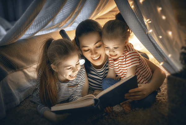 Woman and two children reading by torchlight