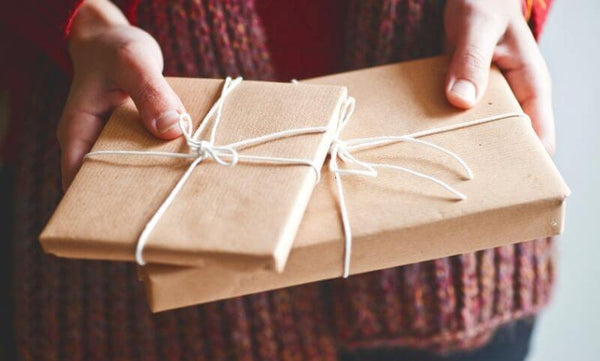 Hands holding two wrapped parcels that look like they contain chapter books