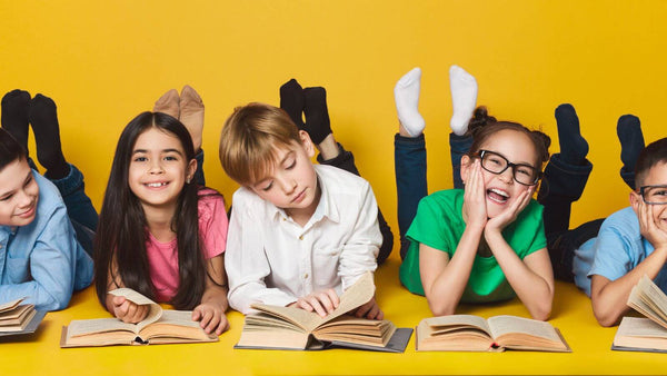 Children lying on their fronts reading books, against a yellow background