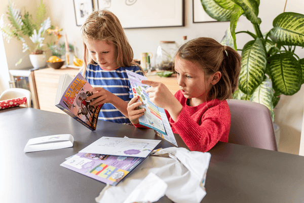 Two children enjoy Parrot Street Book Club subscription box whilst sat at a table