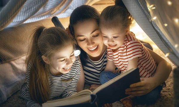 Mother and two kids reading Christmas books by torchlight