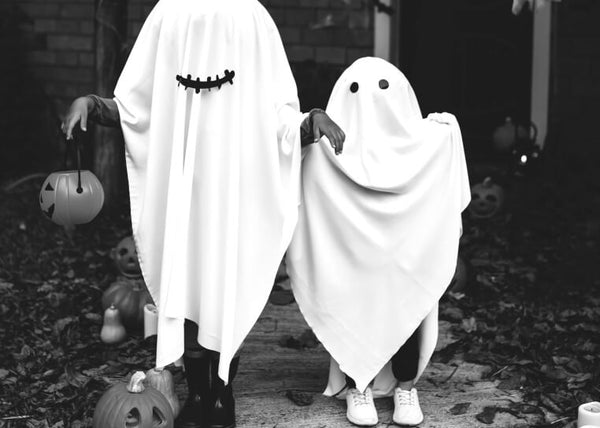 Two kids in white sheets, dressed as ghosts
