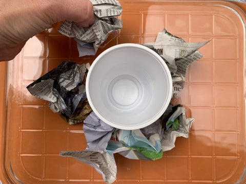 Scrunched paper balls surrounding the cup to make the body of the volcano